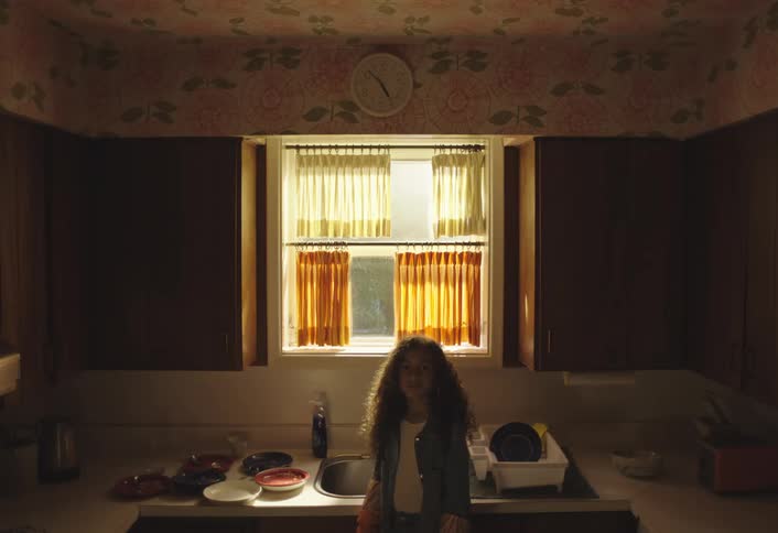 The girl is standing by the sink in the kitchen