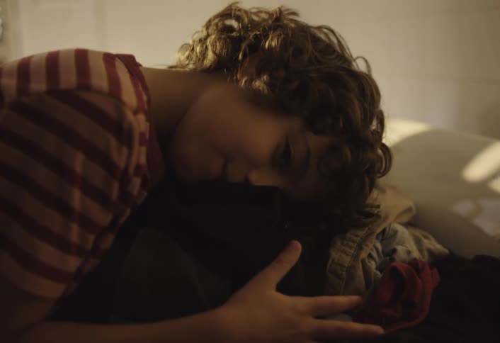 The boy hugs a pile of laundry
