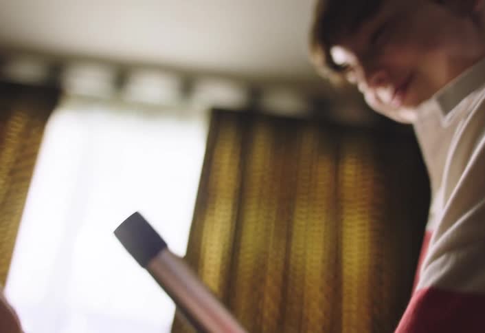 A boy looks through and plays around with a thin metallic tube in a living room