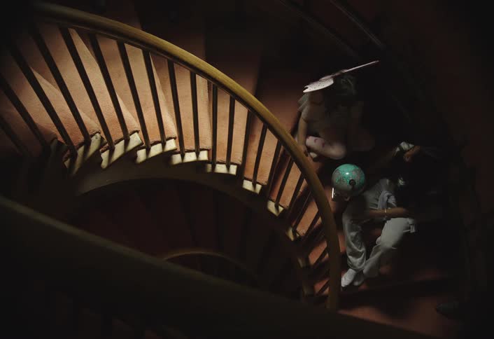 Two little sisters sit on a winding staircase spinning a globe