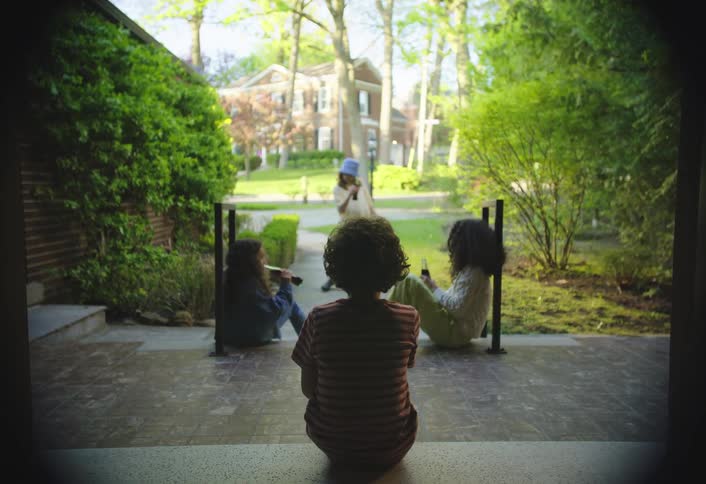 Four children in a backyard drinking from soda bottles