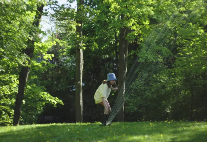 The girl lifts the sprinkler up and plays