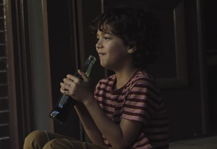 Boy sitting drinking soda from a bottle