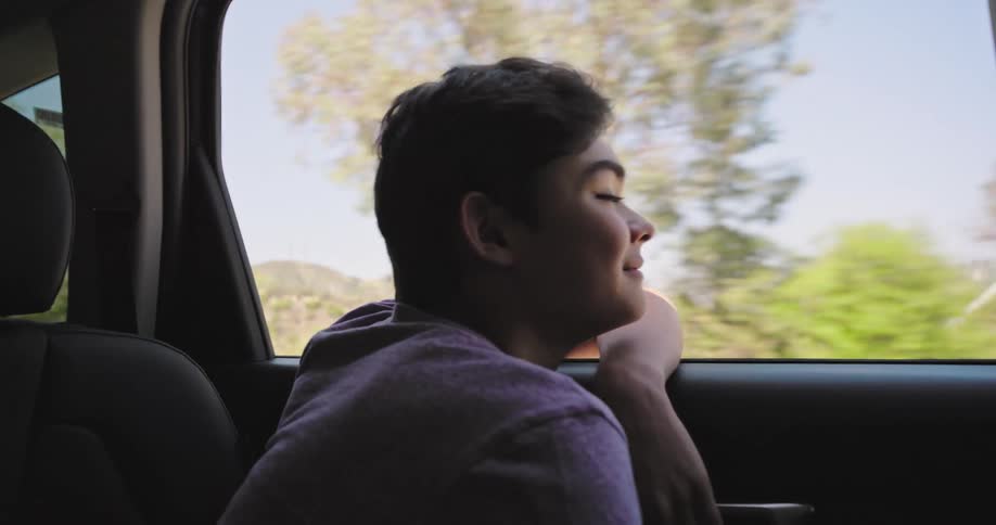 Boy with happy expression in the window of a moving car