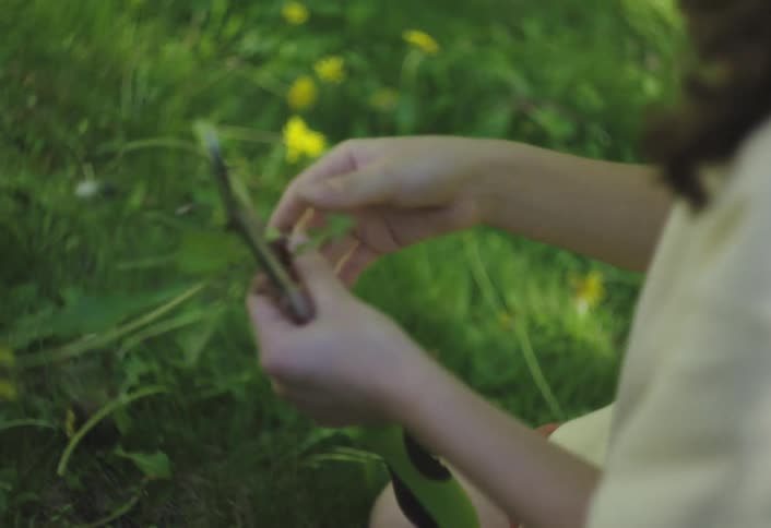 The girl is looking at a flower she dug up