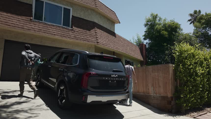 Group of friends getting out of a black suv in a suburban driveway on a sunny day