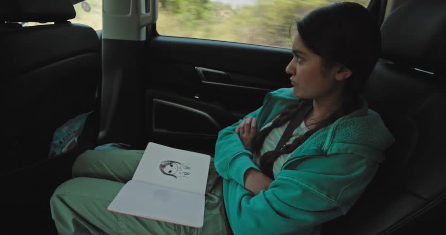 Sulking girl closing a notebook and crossing her arms inside a moving car
