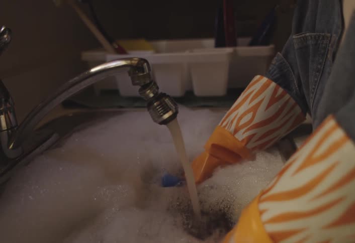 Child with gloves washing dishes