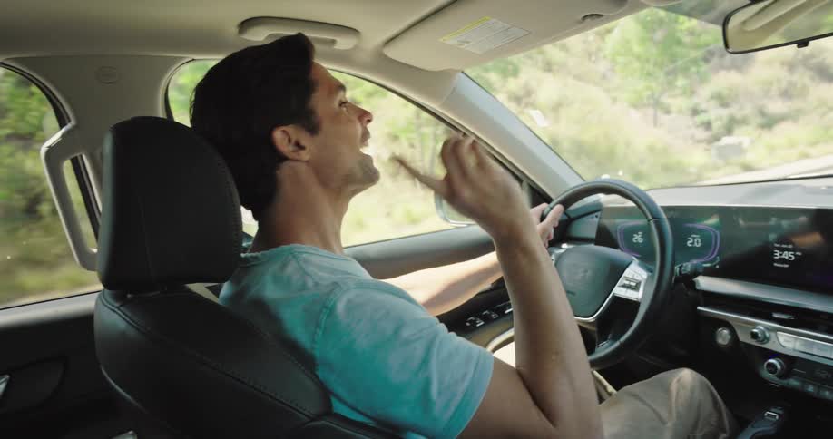 A father is driving a car with his child in the passenger seat singing along to music and enjoying the ride the child is eating snacks from a bag participating in the lively atmosphere of the car journey