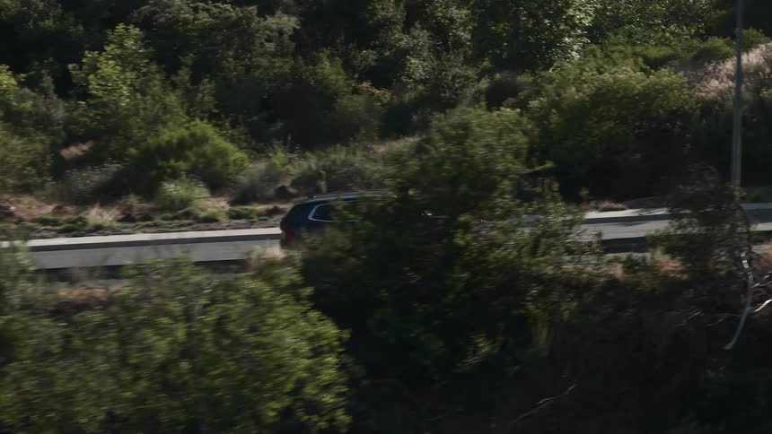 Black suv car traveling on an asphalted area surrounded by trees and mountains