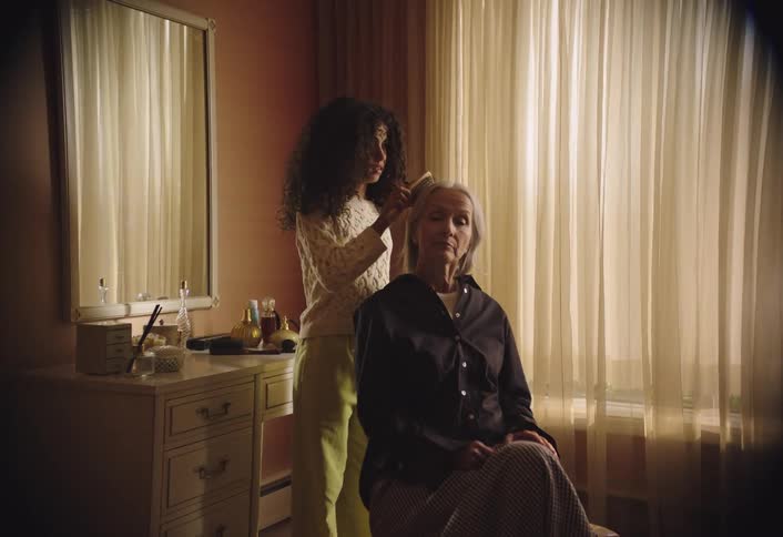 A woman is brushing an older womans hair