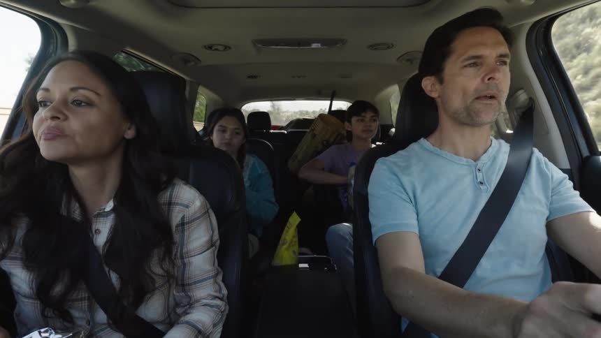 Family inside a car on a road trip eating snacks