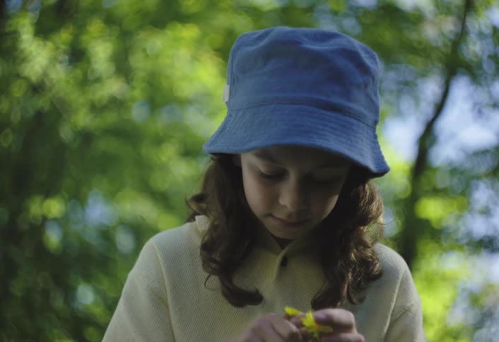 Girl picks yellow wildflowers while outdoors near the trees