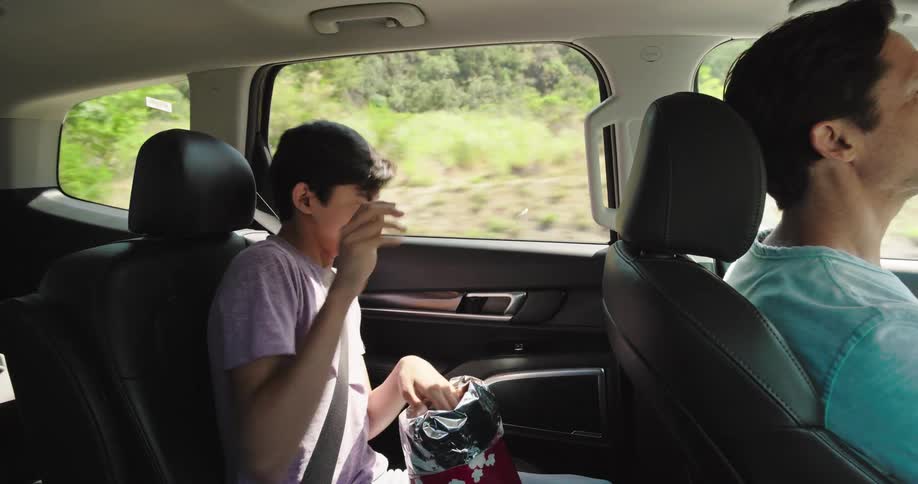 Boy throwing chips into the front seat of a moving car