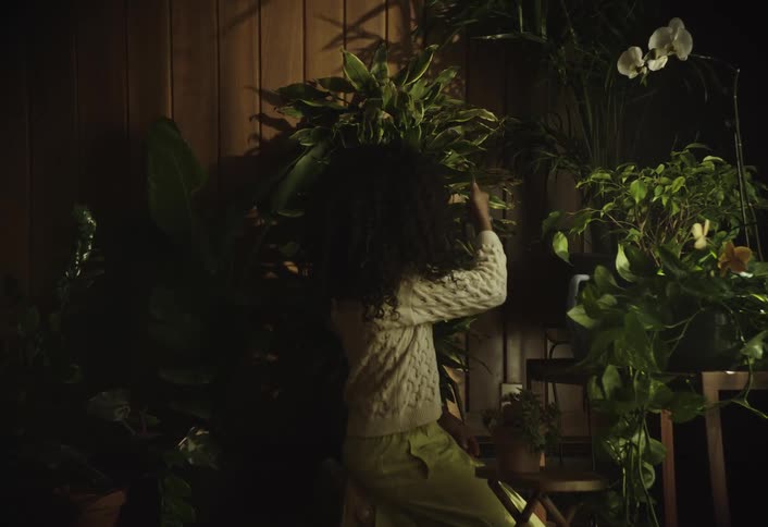 Girl watering plants in an indoor part of the house