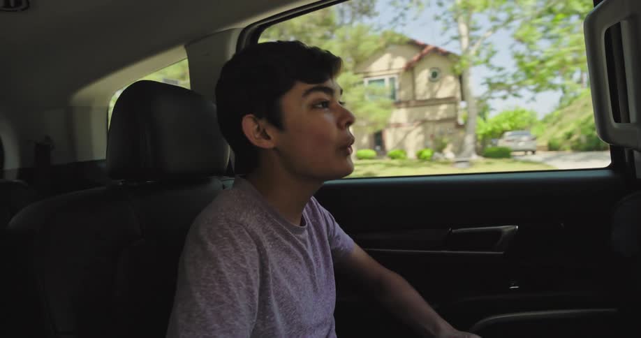 Boy having fun in the backseat of a moving car while his father is driving