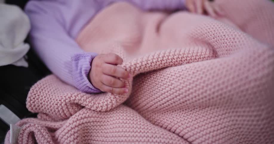 Young child lies under a pink blanket