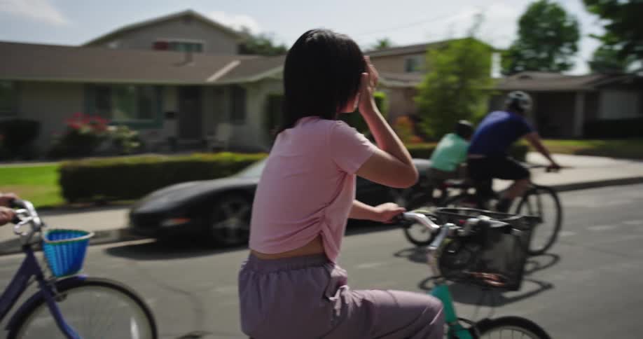 A group of people is riding bikes in the middle of the street in a suburban area at midday