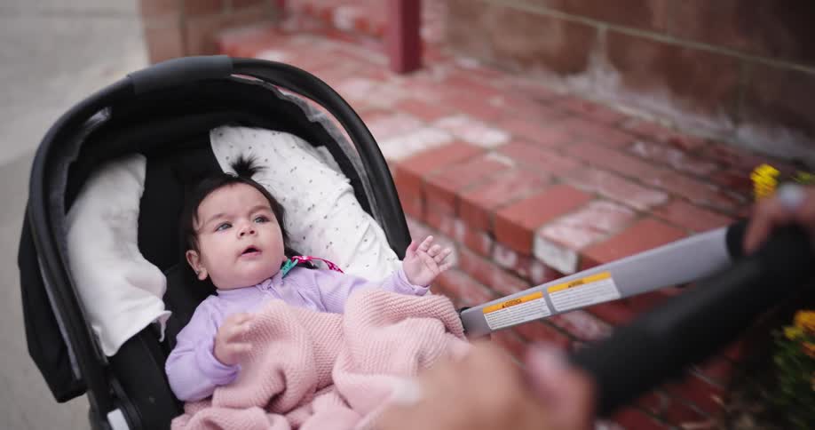 Smiling mother walking with her baby daughter in a stroller