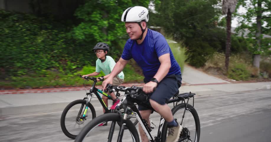Father and son ride bicycles through a neighborhood
