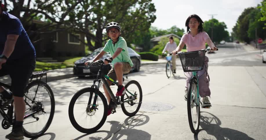 A family is riding bicycles down a suburban street on a sunny day