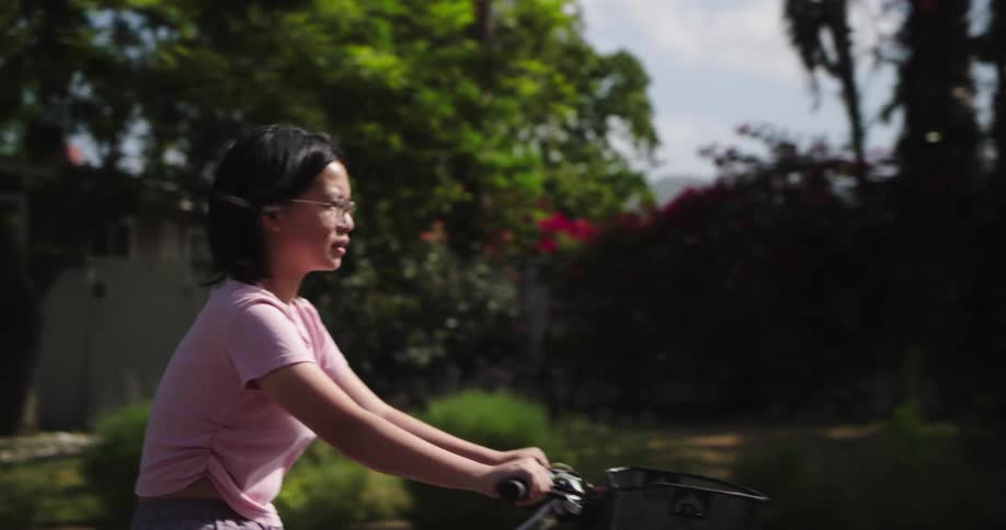 A young girl is riding a bike passing by a man who is also riding a bike on the street at midday
