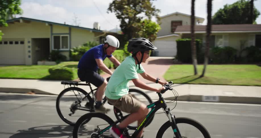 Father races his son while a family pedals along a residential street