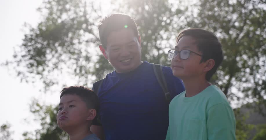 Father hugging his two children in an outdoor setting