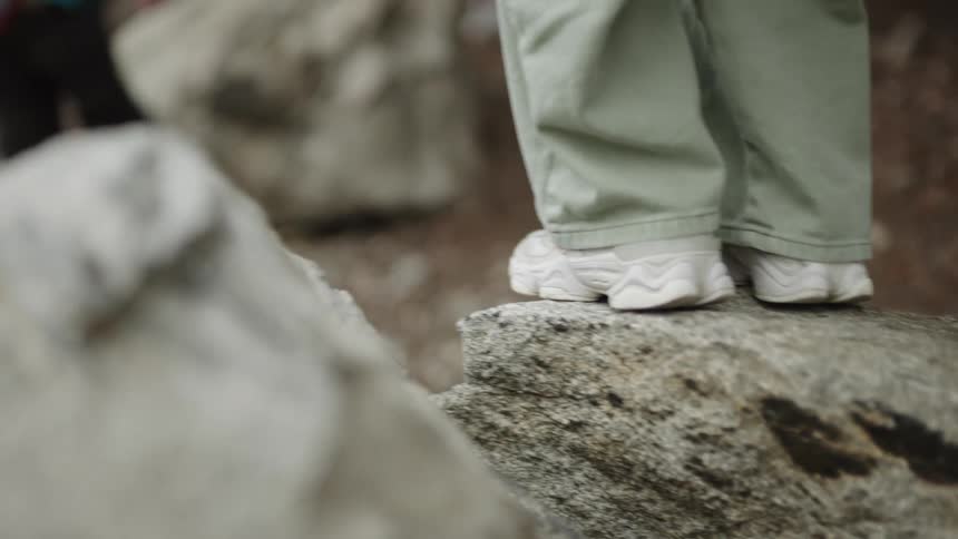 Two children walking on large rocks and hiking in a forest
