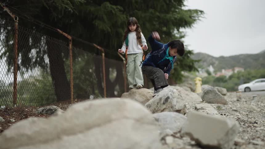 Two children balancing on stones in an outdoor setting