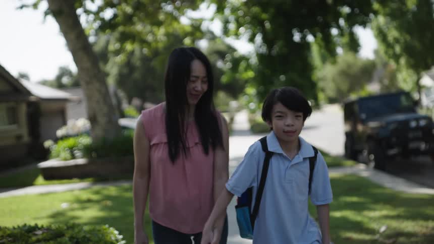 A mother is walking with her son on the sidewalk
