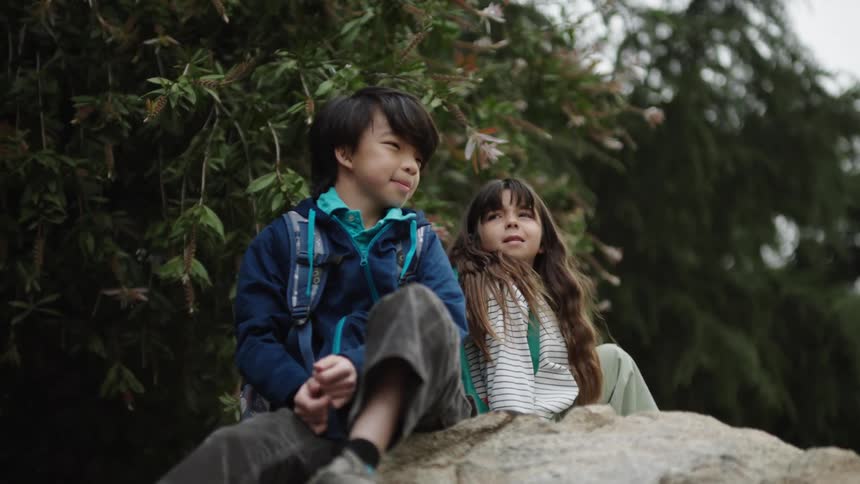 Two children climb over the boulder