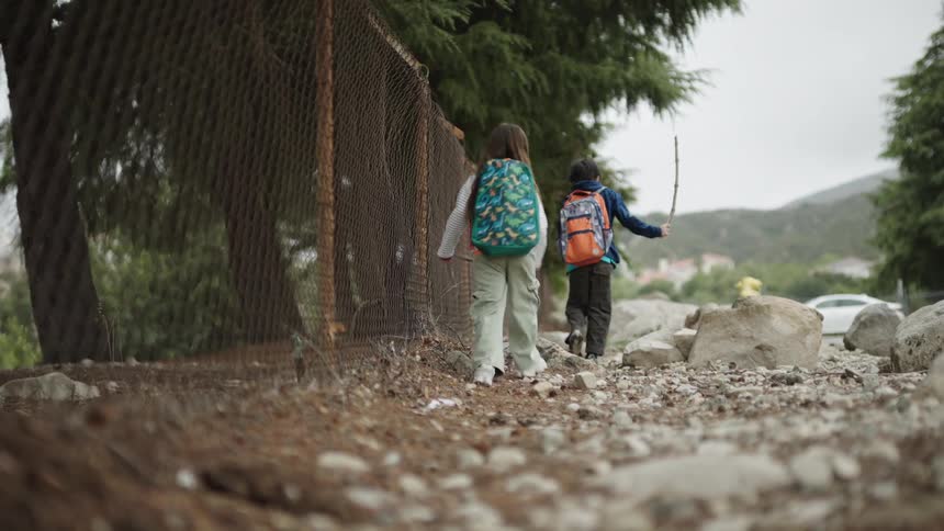 Two children with backpacks walking in an outdoor rocky environment