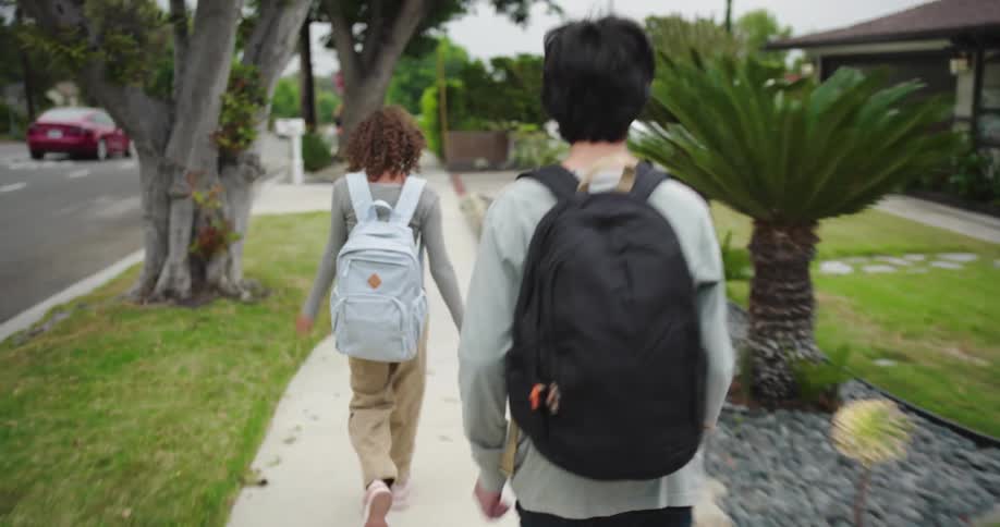 Two teenagers running on a suburban sidewalk