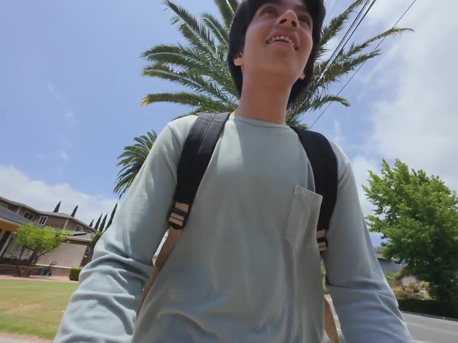The video captures a person with a backpack riding a bike on a sunny day the camera likely mounted on the bike provides a pointofview shot showing various trees and houses along the road