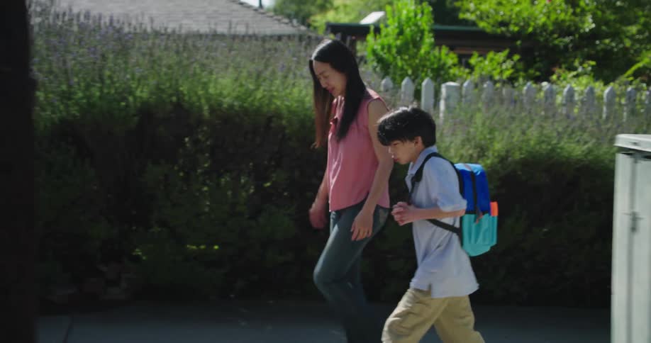 Mother walking with her son on the sidewalk of an urban neighborhood
