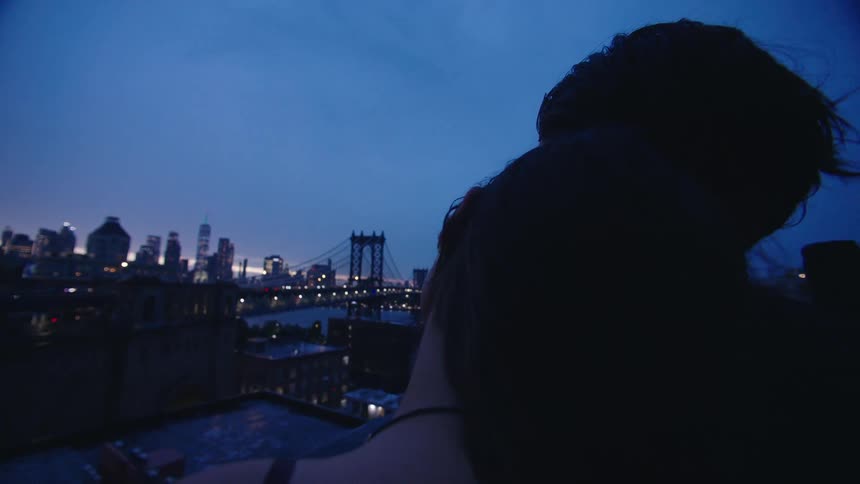 Couple hugging each other watching the panoramic view of a city at dusk