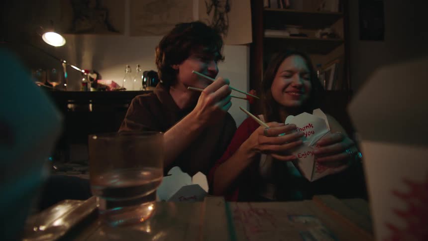 A couple enjoys takeout food and conversation during a cozy night in
