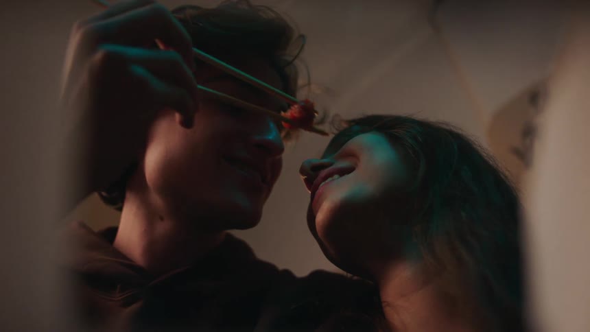 Close up of a young man playfully attempting to feed his female partner indoors