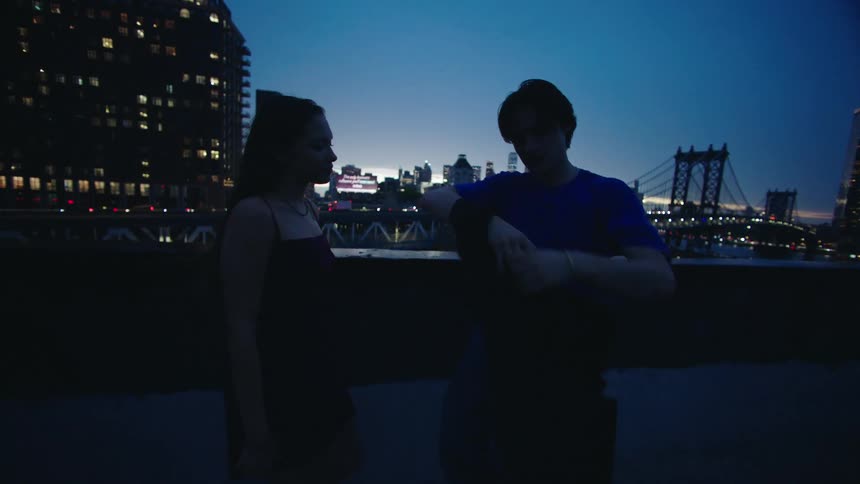 Man putting a coat on a woman on the terrace of a building at night