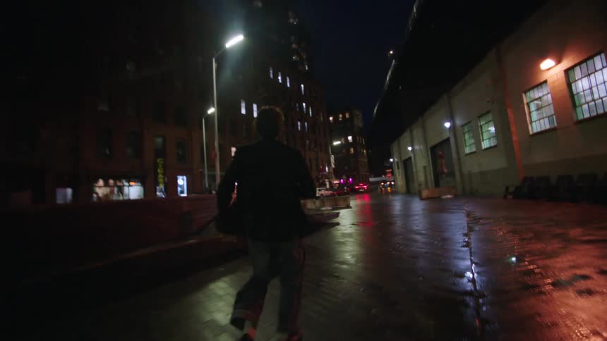 A woman jumps up on the bench at night while a man follows