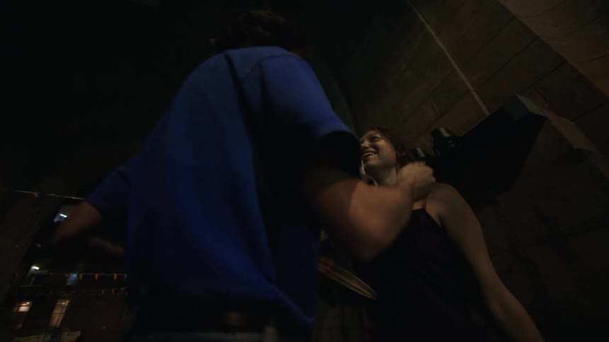 A man and woman hug and walk by the building