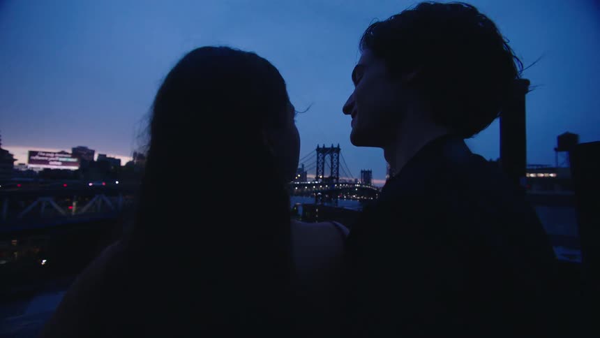 Couple hugging enjoying the view of a city with highways at dusk