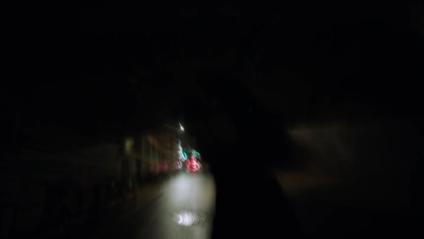 Man and woman run down the middle of a city street and under a bridge at night