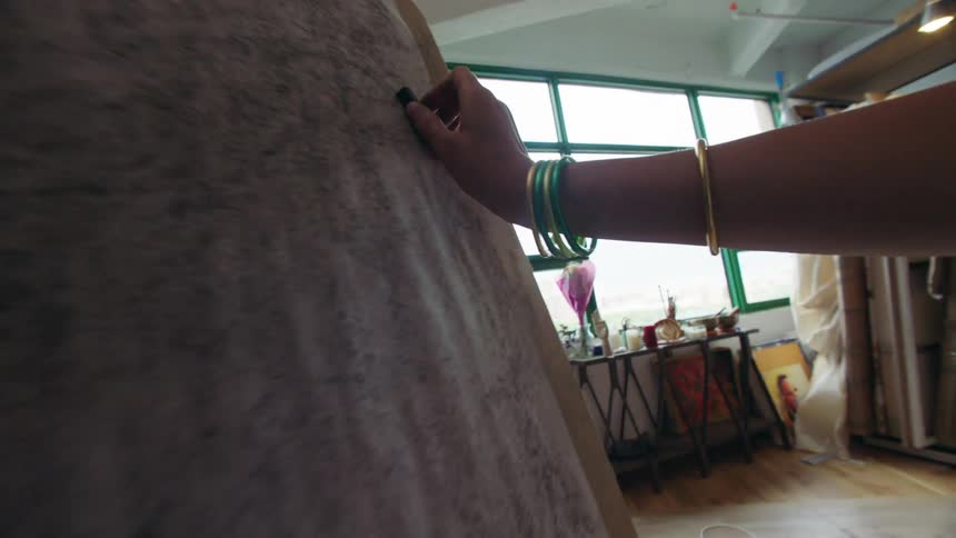 A woman is drawing with charcoal on the canvas