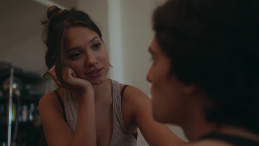 The video shows two individuals engaged in a conversation or intimate interaction with one persons face clearly visible and the others face partially obscured as they face each other the setting appears to be indoors with soft lighting