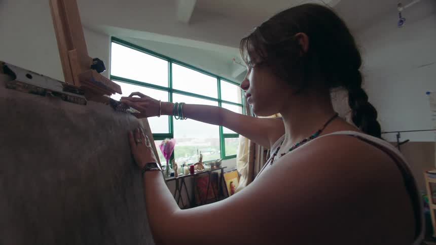 A woman pins a paper to the canvas