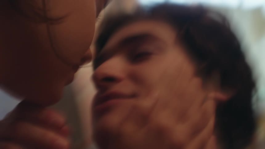 A man and woman grab each others face to kiss