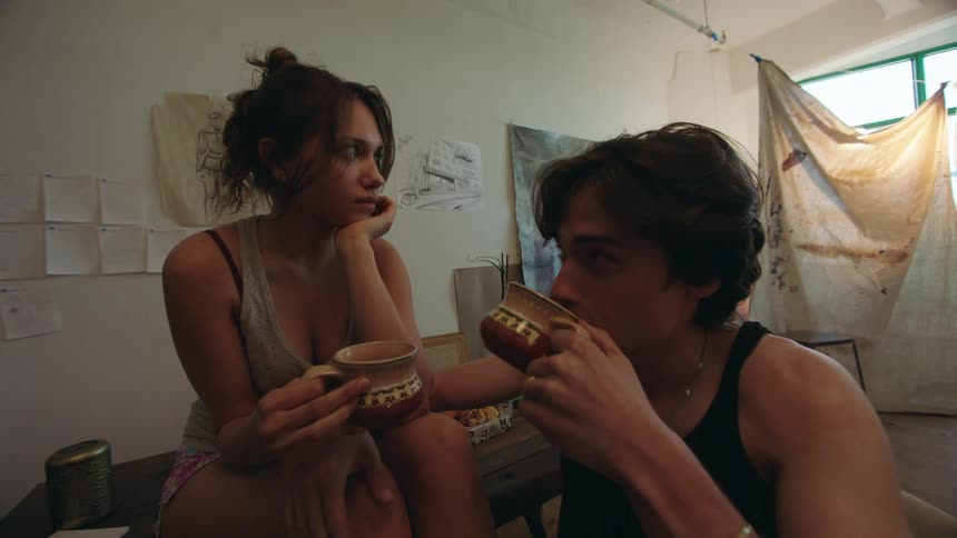A couple enjoys a cozy conversation over drinks in a relaxed artfilled studio