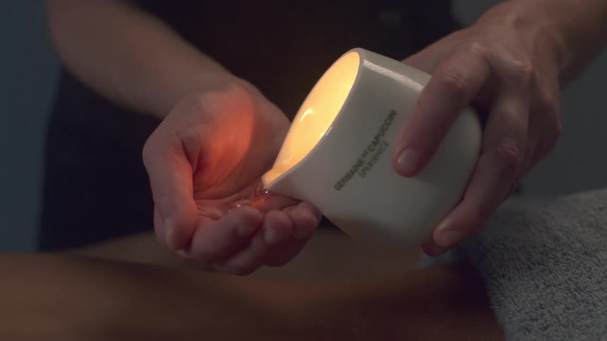 A massage therapist pours wax in her hand